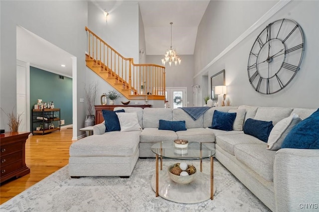 living area with stairs, wood finished floors, a towering ceiling, and an inviting chandelier