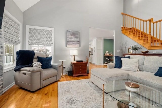 living area featuring high vaulted ceiling, stairs, and wood finished floors