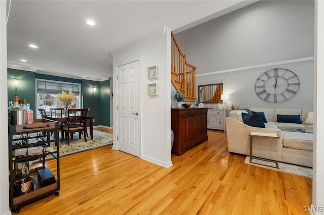 living area with recessed lighting, crown molding, light wood-style flooring, and stairs