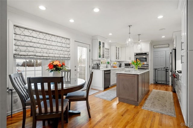 kitchen featuring stainless steel appliances, plenty of natural light, light wood-style flooring, and a center island