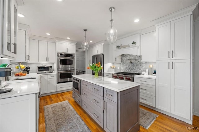 kitchen featuring stainless steel appliances, light wood-style flooring, gray cabinetry, white cabinets, and a sink