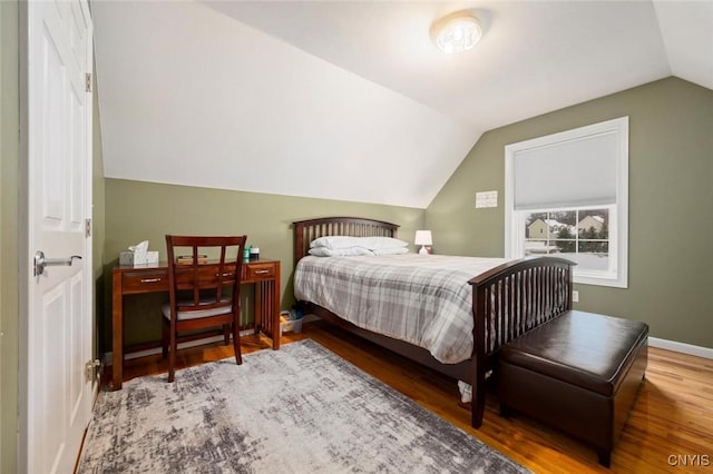 bedroom with vaulted ceiling, wood finished floors, and baseboards