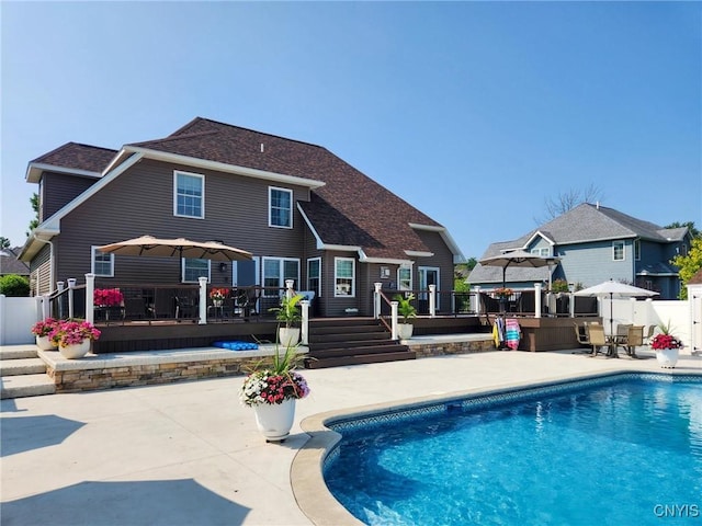 back of house with a patio area, a wooden deck, a fenced in pool, and fence