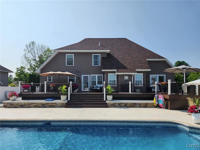 back of house with a fenced in pool, roof with shingles, a patio, and a deck