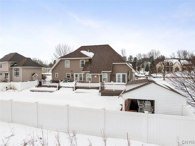 snow covered property featuring a wooden deck, a residential view, and fence