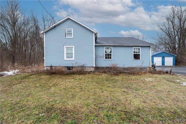 view of side of home with a yard, a detached garage, and an outbuilding