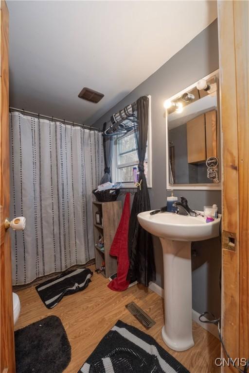 full bath with a shower with shower curtain, wood finished floors, and visible vents