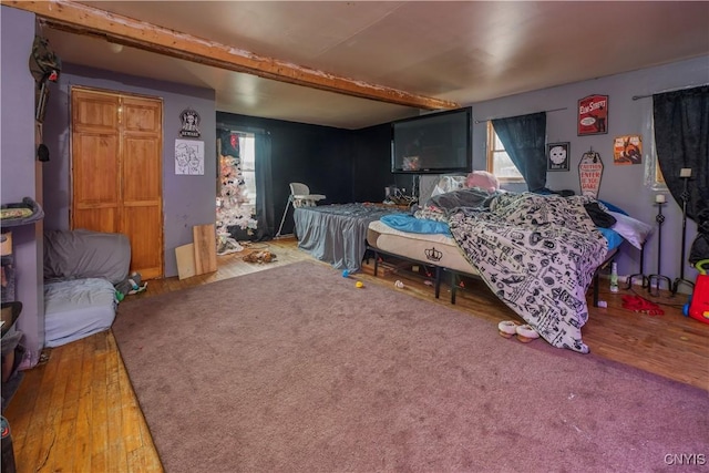 bedroom featuring wood finished floors and beam ceiling