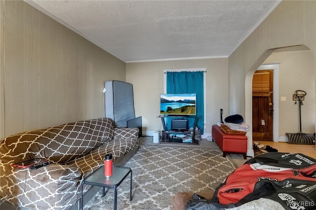 living area featuring arched walkways, a textured ceiling, carpet flooring, and crown molding