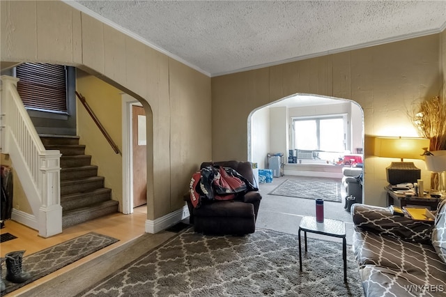 living room featuring arched walkways, ornamental molding, a textured ceiling, and stairs