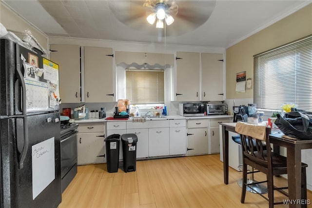 kitchen featuring a toaster, light countertops, light wood-style floors, white cabinets, and black appliances