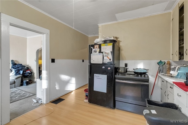 kitchen featuring range with electric stovetop, visible vents, ornamental molding, light wood-type flooring, and freestanding refrigerator