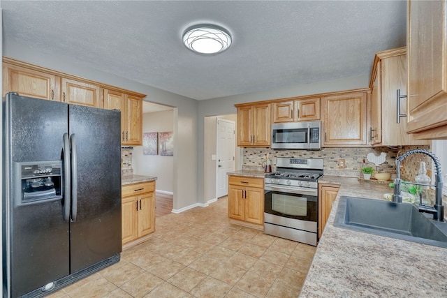 kitchen with stainless steel appliances, a sink, baseboards, light countertops, and tasteful backsplash