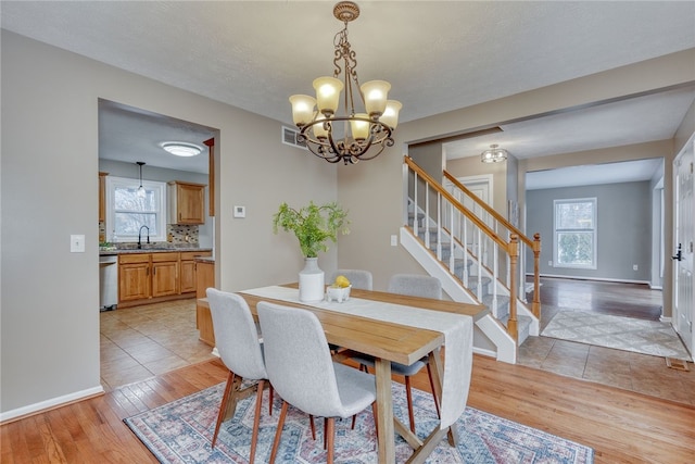 dining space with a wealth of natural light, baseboards, stairway, and light wood finished floors