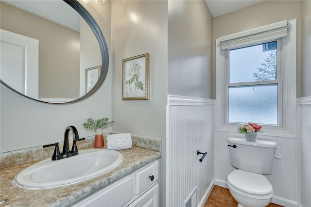 bathroom with toilet, tile patterned floors, a wealth of natural light, and vanity