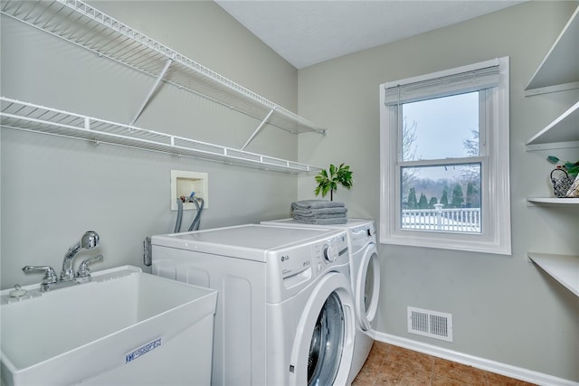 washroom featuring laundry area, separate washer and dryer, a sink, visible vents, and baseboards