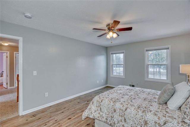 bedroom featuring light wood-style flooring, baseboards, and ceiling fan