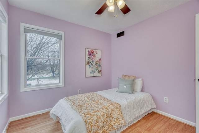 bedroom featuring light wood-type flooring, visible vents, baseboards, and a ceiling fan