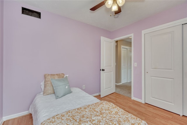 bedroom with light wood finished floors, a ceiling fan, and baseboards