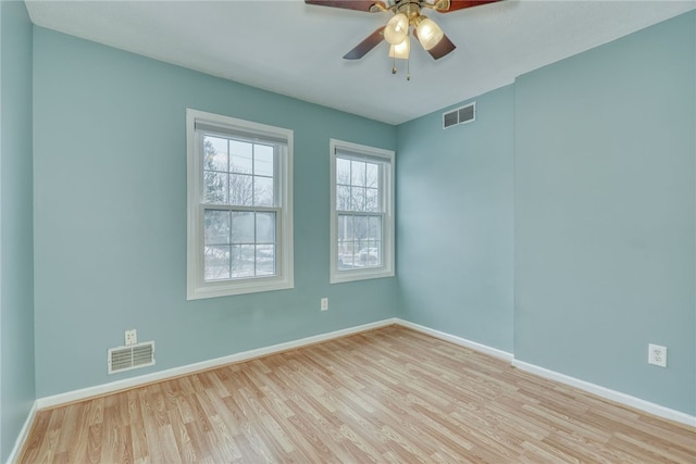 spare room with a ceiling fan, baseboards, visible vents, and wood finished floors