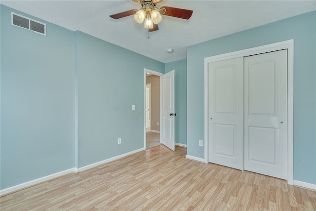 unfurnished bedroom with baseboards, a closet, visible vents, and wood finished floors