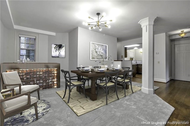 dining area featuring a chandelier, decorative columns, baseboards, and wood finished floors