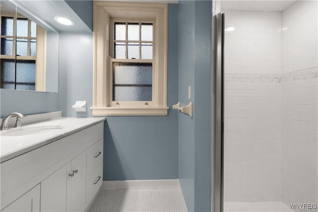 full bathroom with a stall shower, tile patterned flooring, vanity, and baseboards