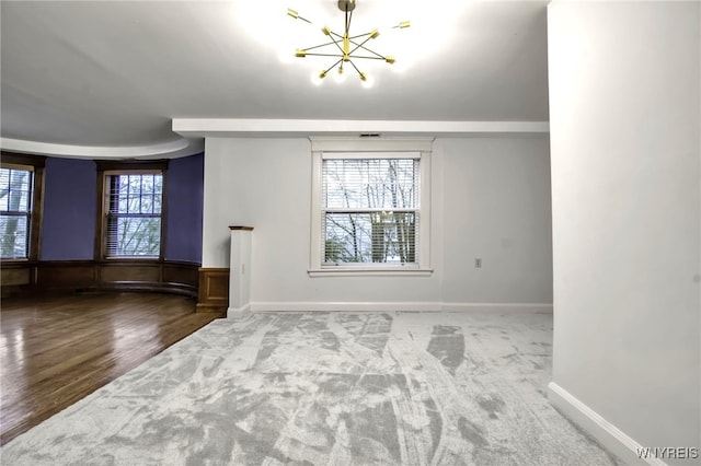 unfurnished living room featuring baseboards, wood finished floors, carpet flooring, and a notable chandelier