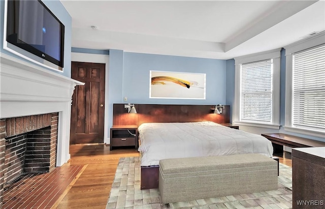 bedroom with a brick fireplace and wood finished floors