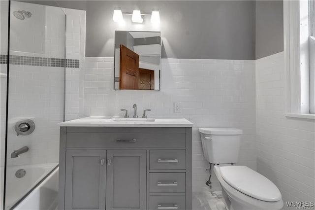 full bath with tile walls, tub / shower combination, vanity, and toilet