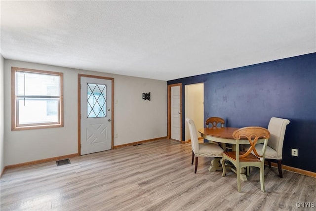 dining space featuring light wood-type flooring, visible vents, and baseboards