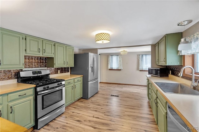 kitchen with stainless steel appliances, light wood-style floors, light countertops, and a sink