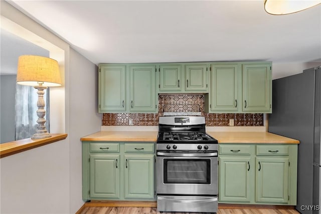 kitchen featuring light wood finished floors, appliances with stainless steel finishes, light countertops, and decorative backsplash