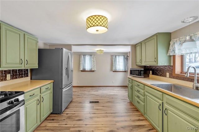 kitchen with appliances with stainless steel finishes, plenty of natural light, green cabinetry, and a sink