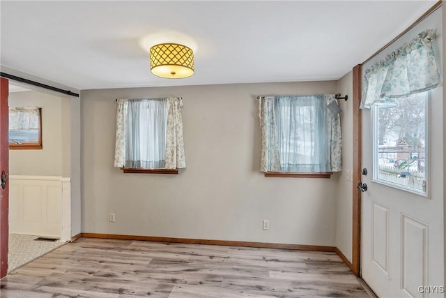 foyer entrance with visible vents, baseboards, and wood finished floors