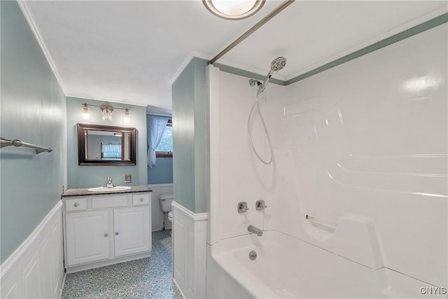 bathroom with a wainscoted wall, toilet, ornamental molding, vanity, and speckled floor