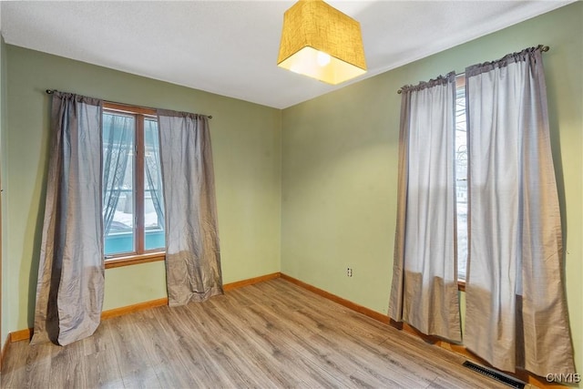 spare room with visible vents, baseboards, and wood finished floors