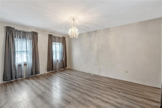 unfurnished room with a chandelier and wood finished floors