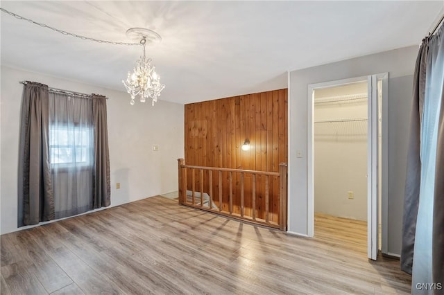 unfurnished room with an inviting chandelier and wood finished floors