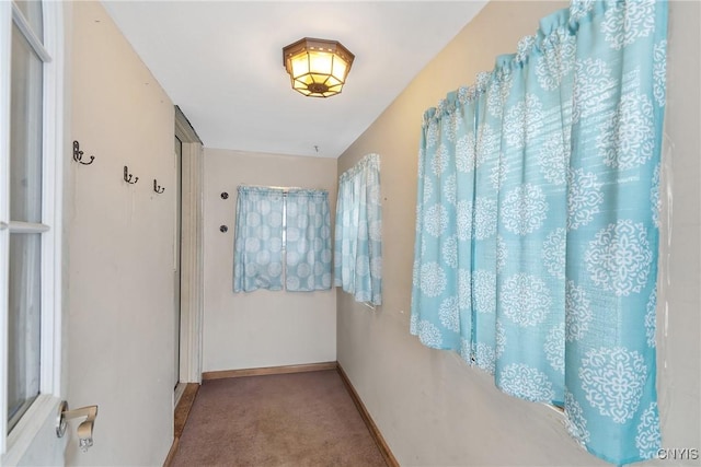 hall featuring carpet flooring and baseboards