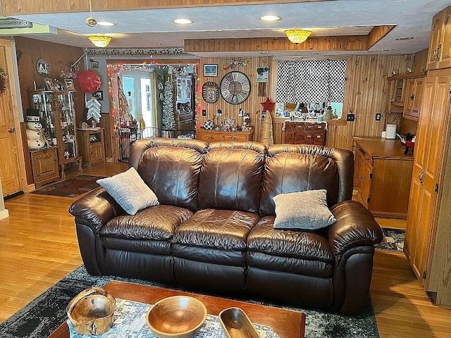 living room featuring a textured ceiling, wood walls, wood finished floors, and recessed lighting