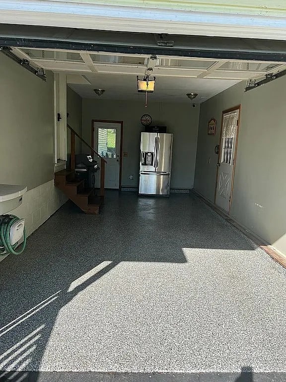 garage featuring stainless steel fridge and a garage door opener