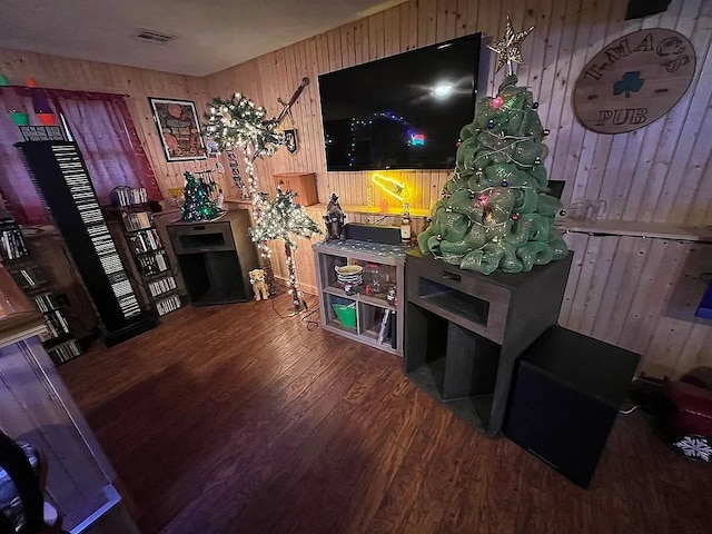 living area with wood walls, visible vents, and wood finished floors