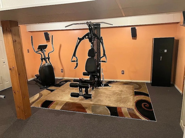 workout area featuring a paneled ceiling, baseboards, and carpet flooring