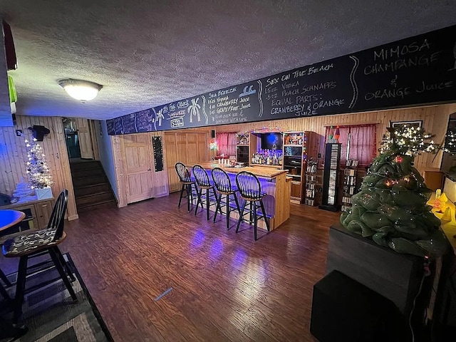 bar featuring a dry bar, a textured ceiling, stairway, and dark wood-style flooring