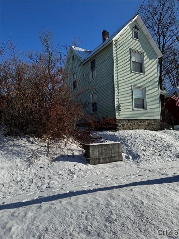 view of snowy exterior featuring a chimney