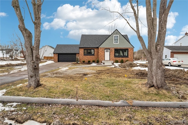 view of front facade with driveway, an attached garage, roof with shingles, and brick siding