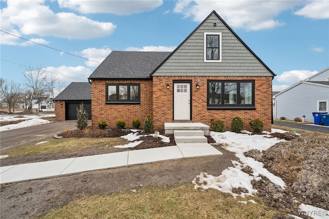 view of front of property with a garage, brick siding, driveway, and roof with shingles