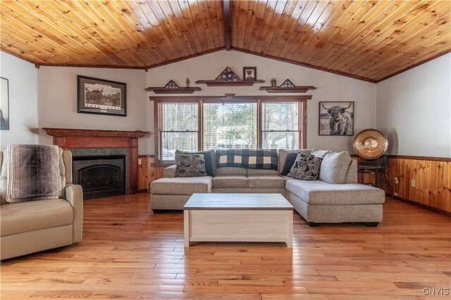 living room with lofted ceiling, a fireplace, wood ceiling, wainscoting, and light wood finished floors