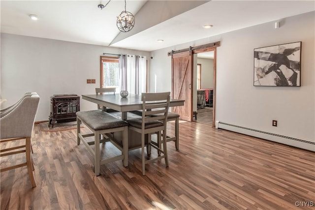 dining area featuring a wood stove, a barn door, wood finished floors, and lofted ceiling